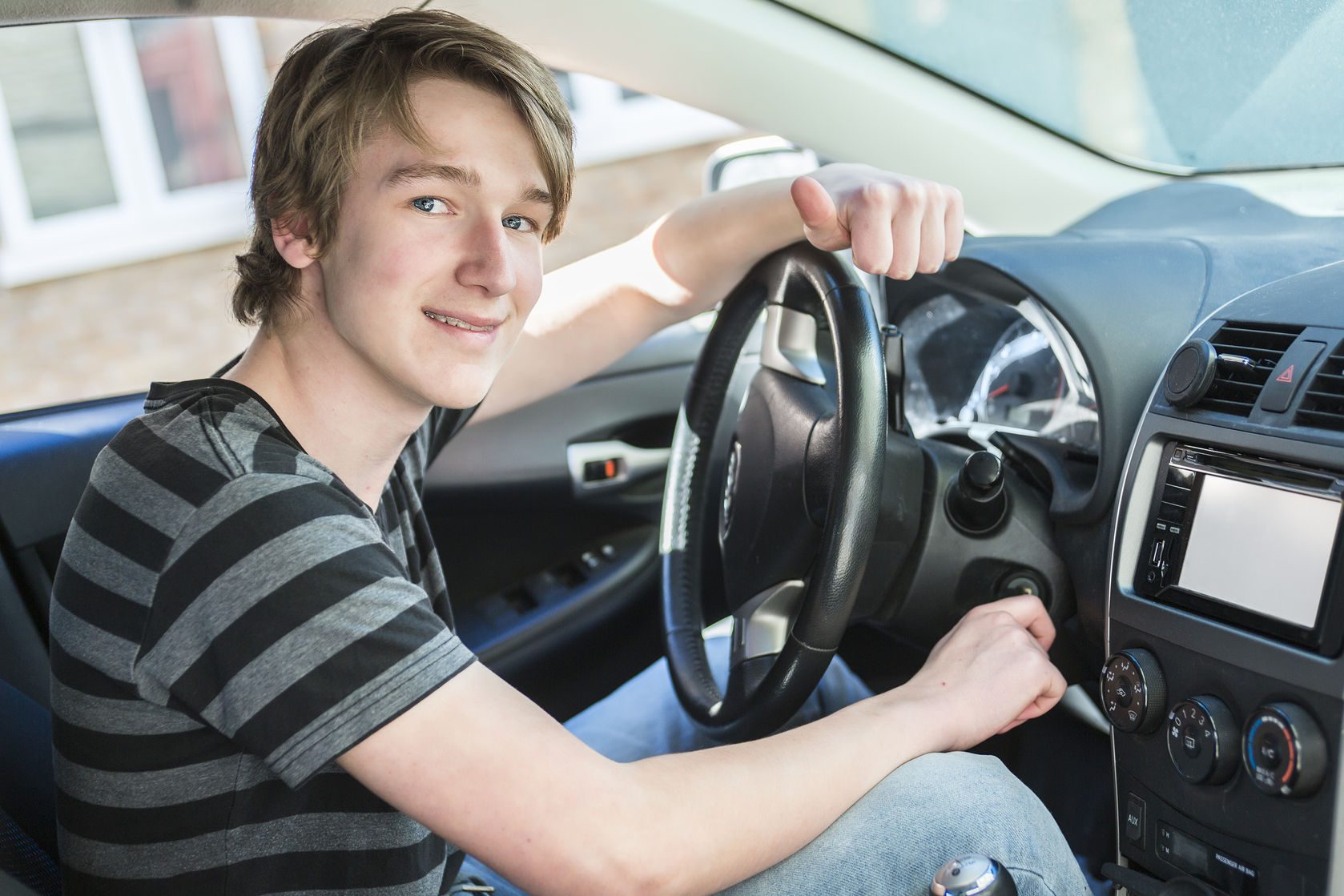 a teenage boy and new driver behind wheel of his car