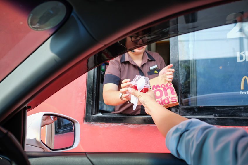 nidentified customer receiving hamburger and ice cream after order and buy it from mcdonald's drive thru service, mcdonald's is an american fast food restaurant chain