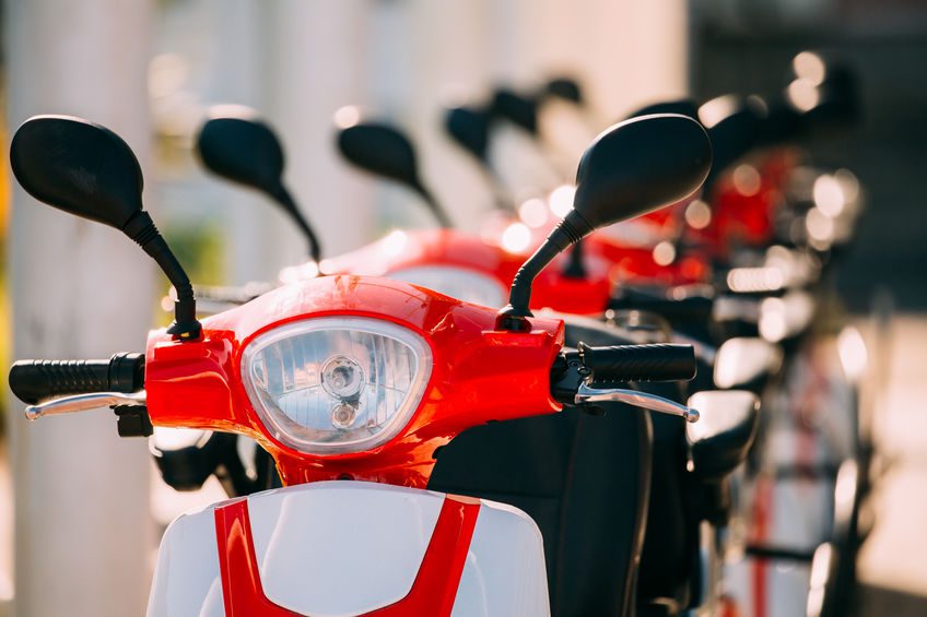 Close Up Of Handlebars Of Many Electric Motorbikes, Motorcycles Scooters Parked In Row In City Street.