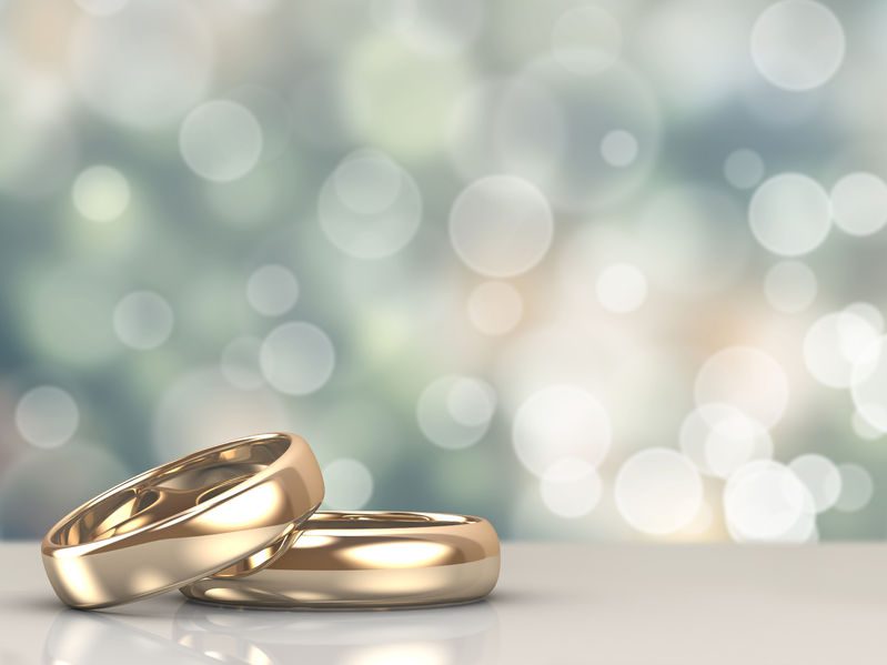 a pair of gold wedding rings with bokeh background